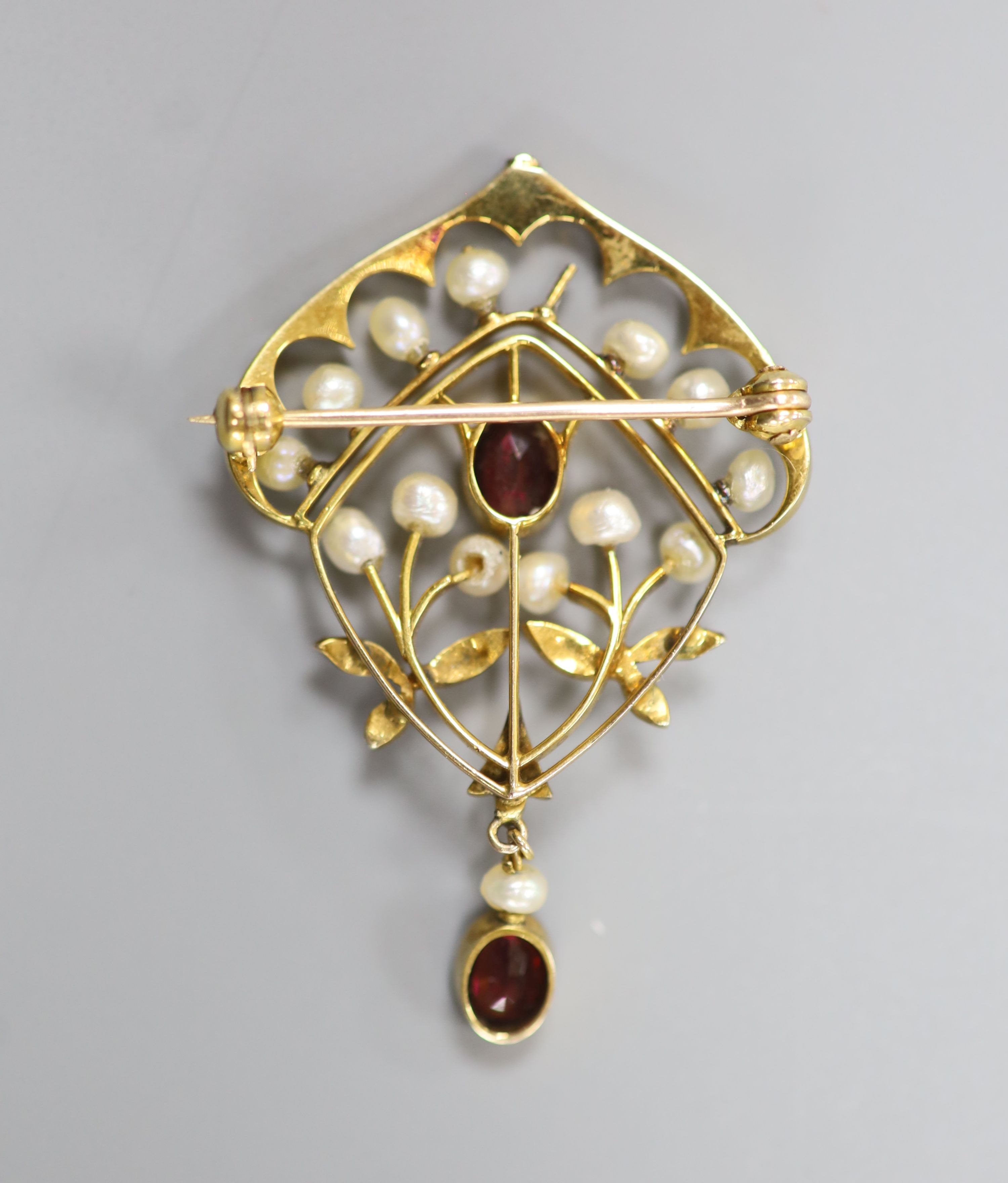 An early 20th century yellow metal, garnet and seed pearl set drop brooch(pearl missing), 47mm, gross 5,2 grams.